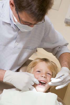 A dentist is performing a dental procedure on a young child in a dental office.