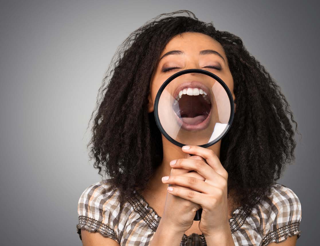 A woman s hand holding a magnifying glass to her mouth, with the magnifying glass covering her lips.