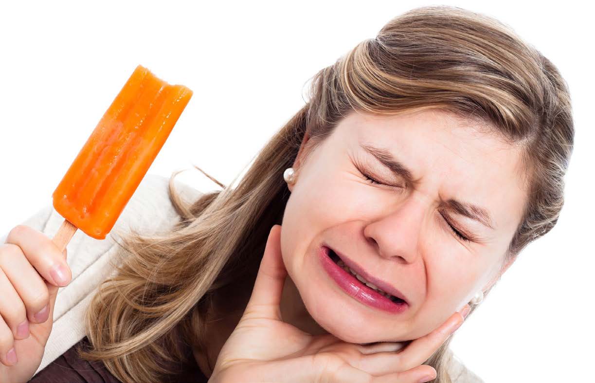 Woman holding a popsicle with her mouth, appearing to be in pain or discomfort.