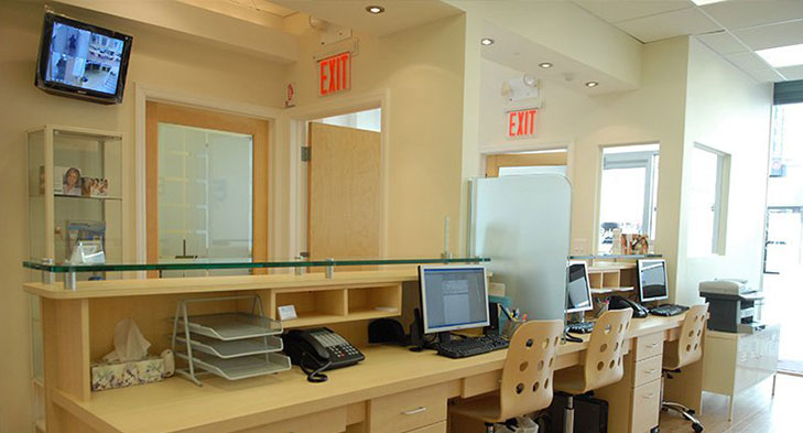 An image of a well-lit office interior with multiple desks, computer equipment, and a reception area.