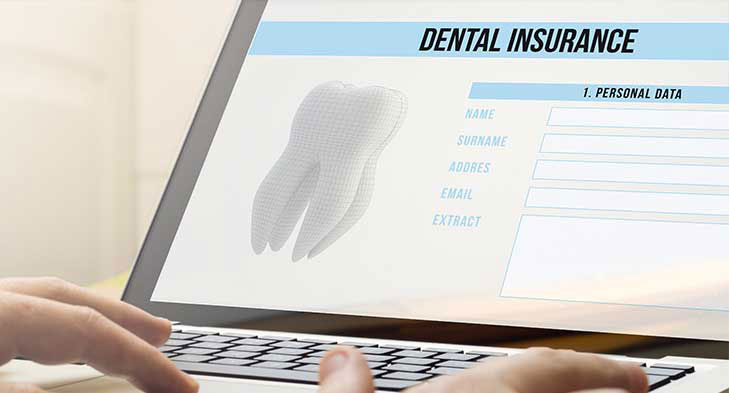 A person s hand interacting with a laptop screen displaying a dental insurance application form.