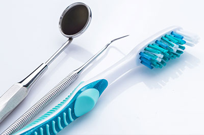 This image features a collection of dental tools, including a toothbrush with blue bristles and several other instruments commonly used in dentistry.