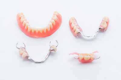 The image displays a set of dental braces with pink acrylic teeth, presented against a white background.