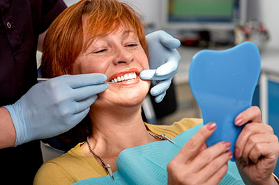 A woman in a dental office, receiving a teeth cleaning from a dentist.