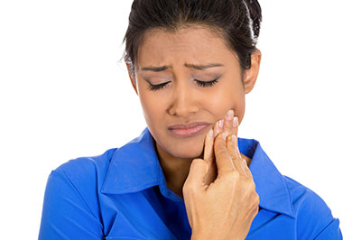 A woman in a blue shirt and white pants, with her mouth open and hand on her face, appears to be reacting with surprise or concern.