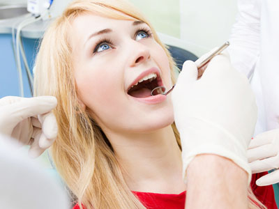 The image shows a woman seated in a dental chair, receiving dental care.